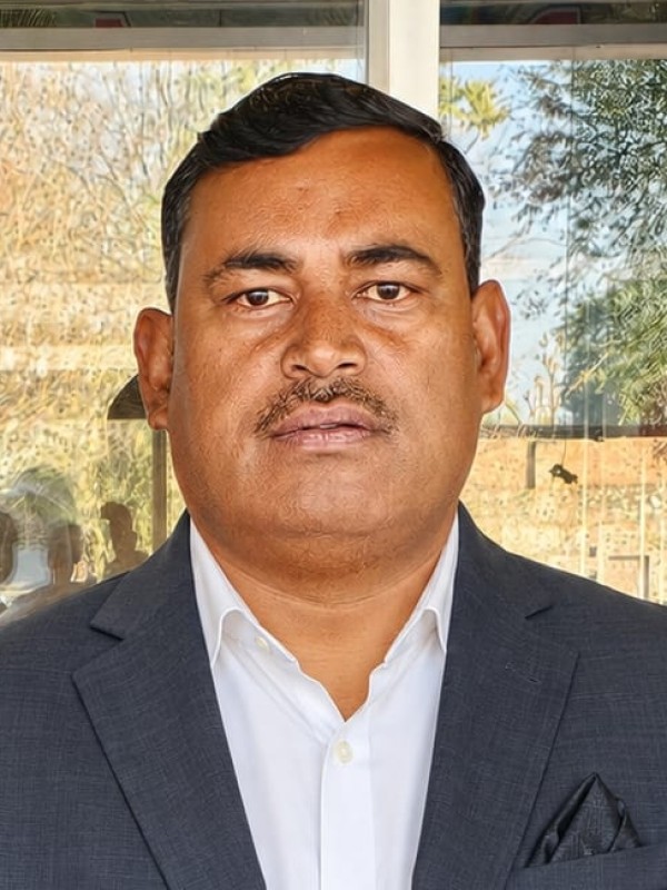 Rakesh Giri, founder of Sai Ram Developers, photographed outside the office in a grey suit.